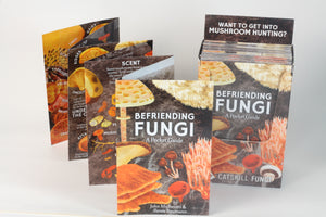 Professional photo of Befriending Fungi: A Pocket Guide by John Michelotti and Renee Baumann. This accordion folded guide is opened up for viewer to see the amazing ways they can be Befriending Fungi as well as a box that holds 25 Befriending Fungi A Pocket Guide .The box reads "Want to get into mushroom hunting?" 